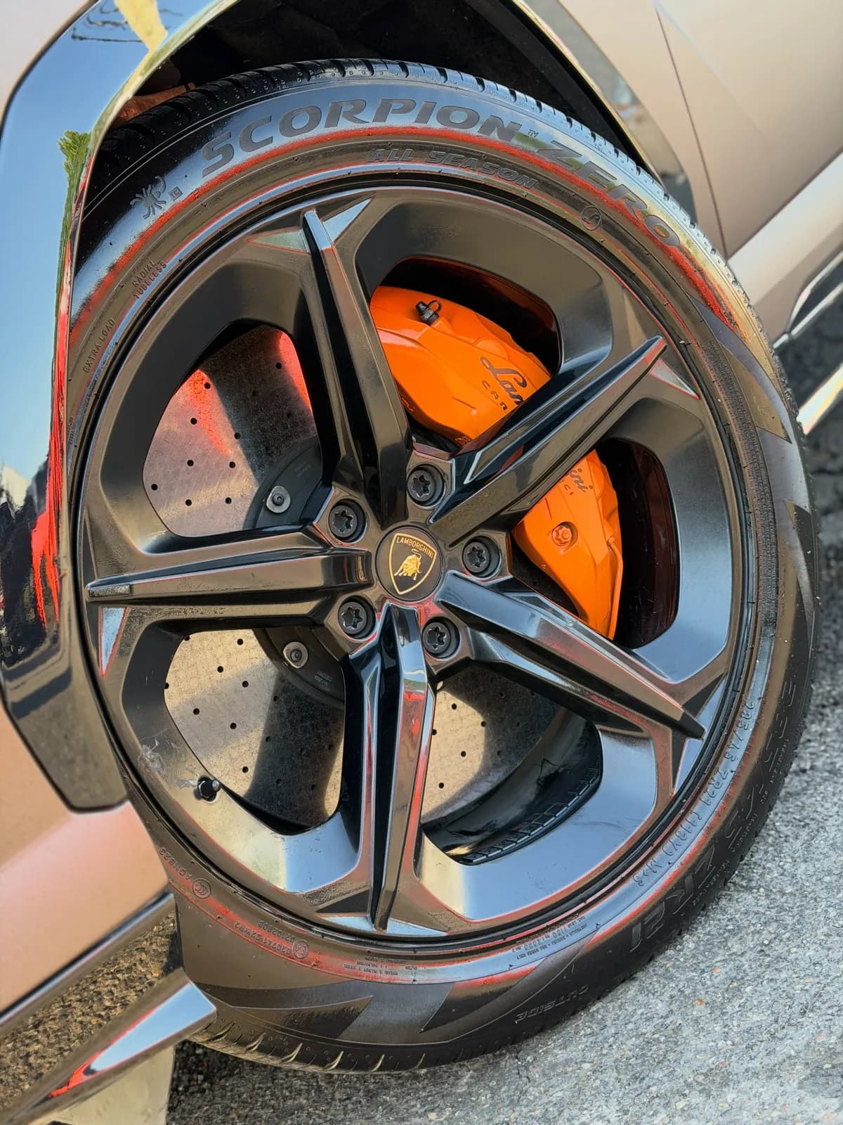 Orange painted brake caliper behind a black wheel on a Lamborghini Urus at Buff X Customization