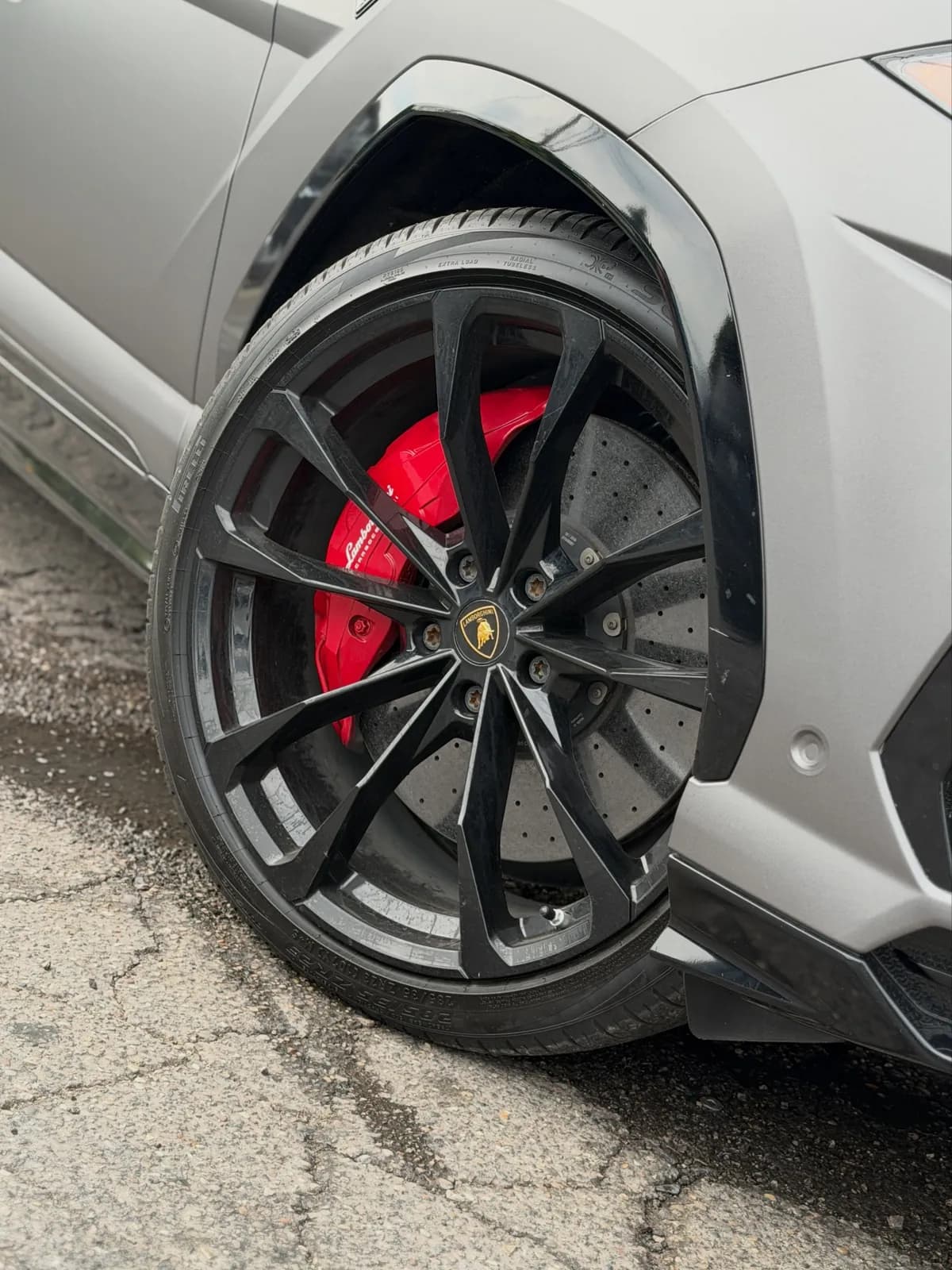 Close-up of a red painted Lamborghini brake caliper on a gray Urus at Buff X Customization