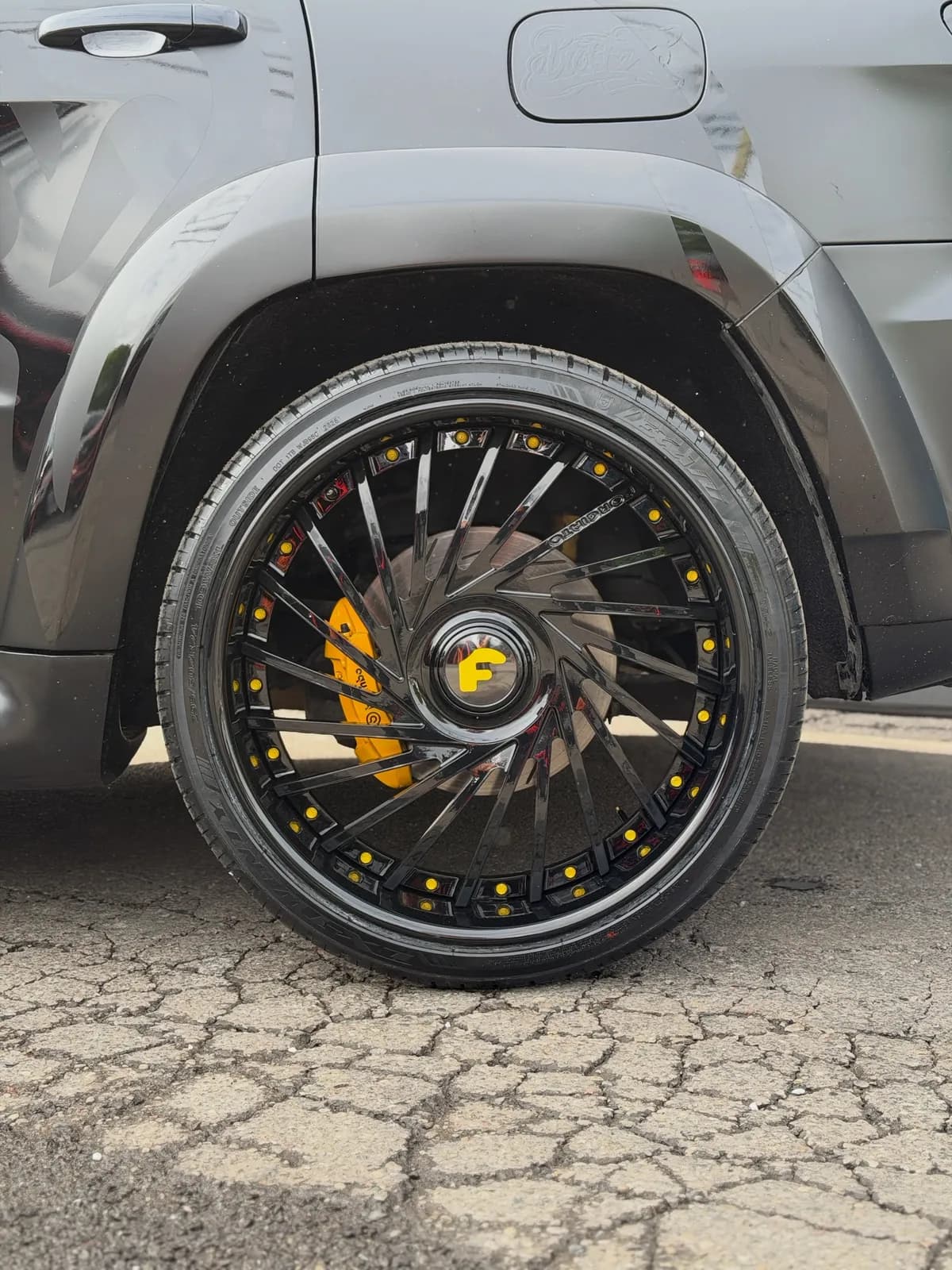 Yellow painted brake caliper behind a black wheel on a Trackhawk at Buff X Customization
