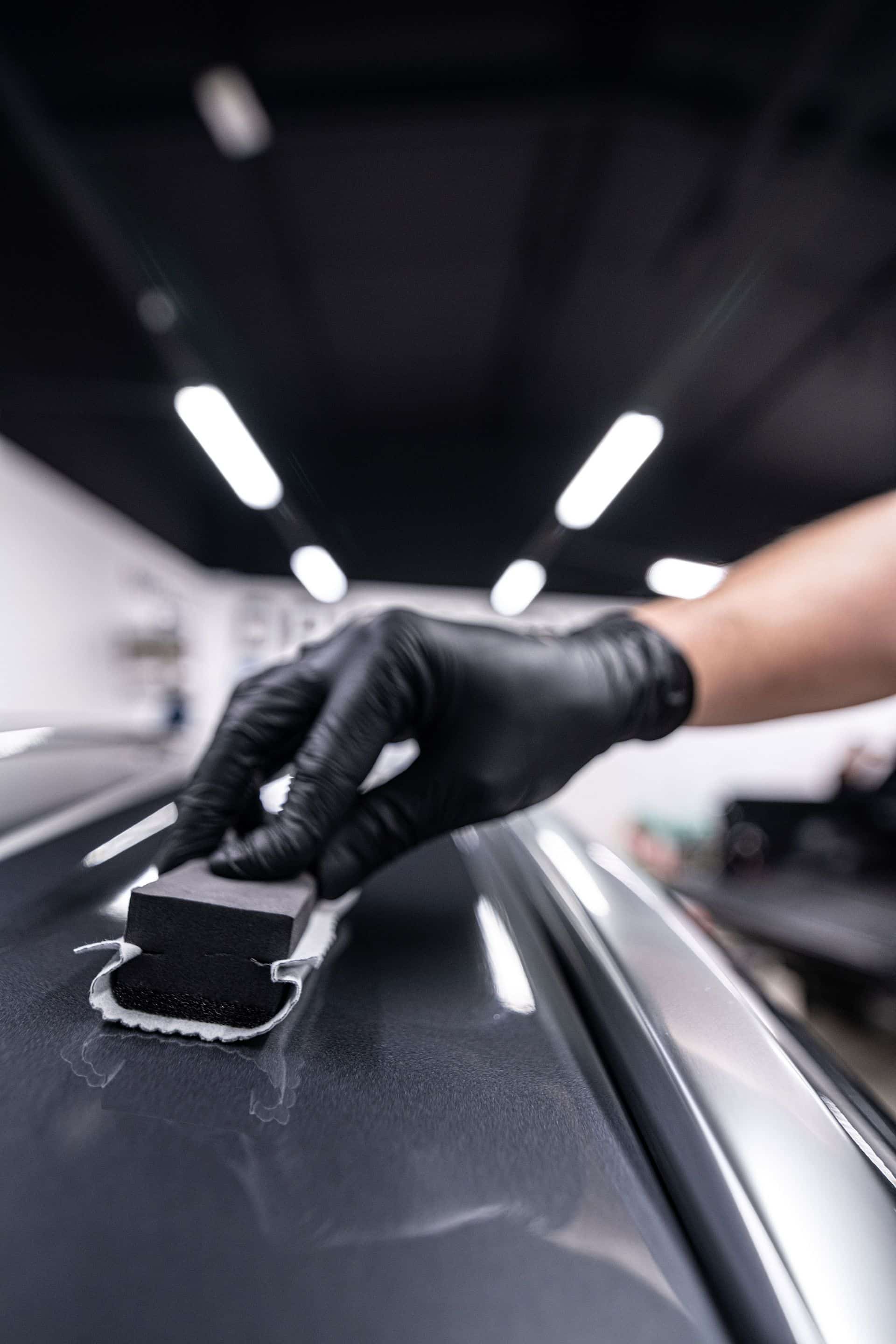 Gloved hands applying ceramic coating to a car