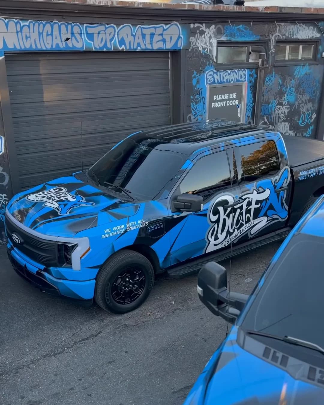 Ford F-150 Lightning with a printed commercial wrap outside Buff X Customization in Dearborn Heights