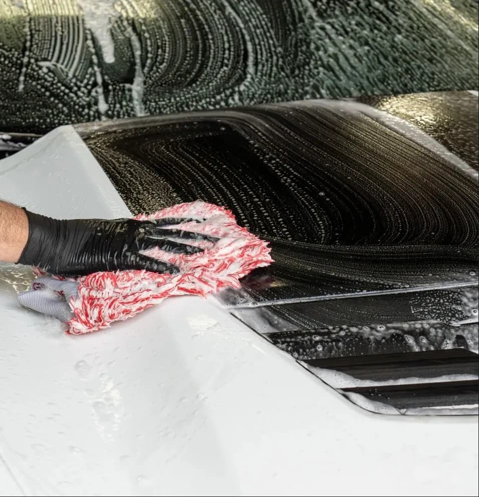 Hand washing a car with a microfiber mitt during a detail at Buff X Customization in Dearborn Heights