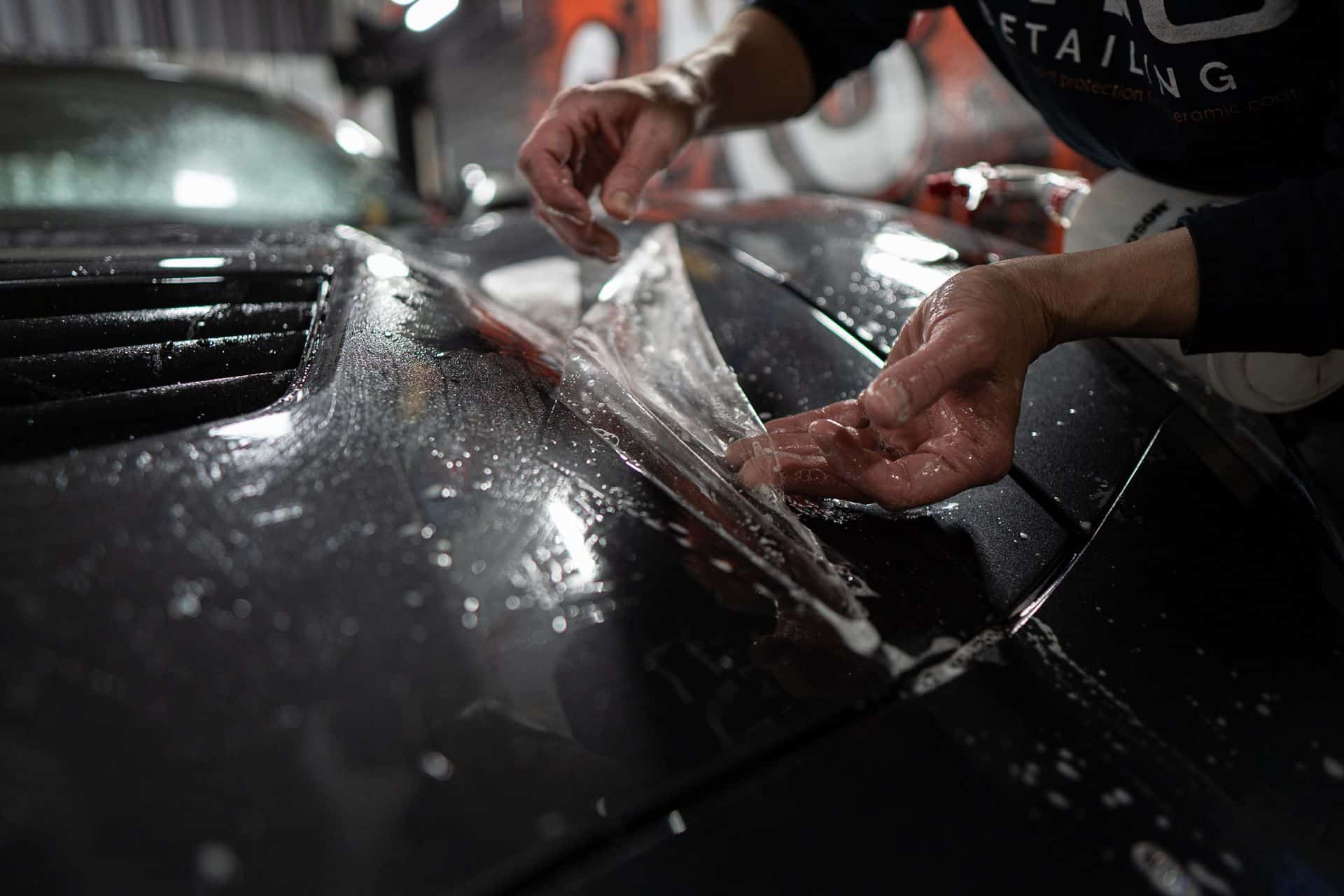 Installer laying wet protection film on a black car