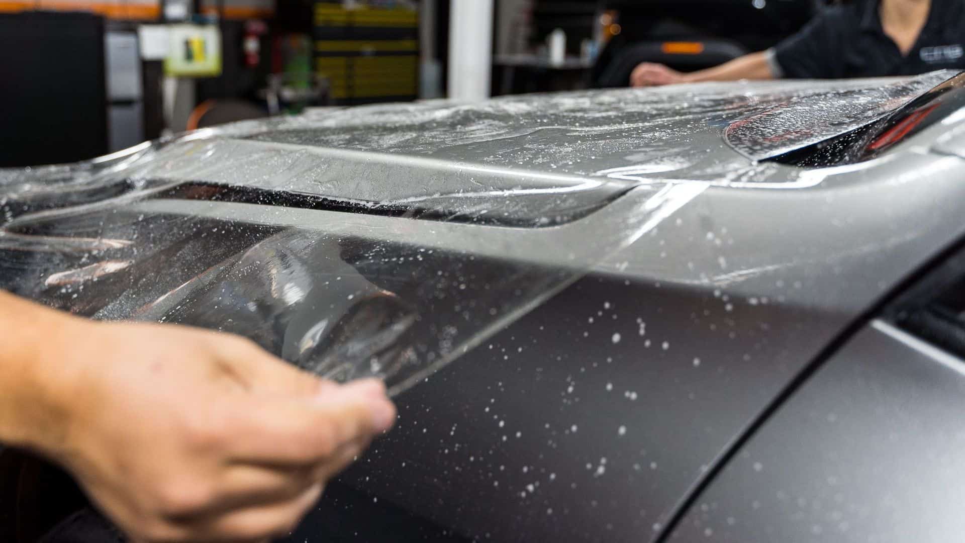 Installer laying paint protection film on a car's paint