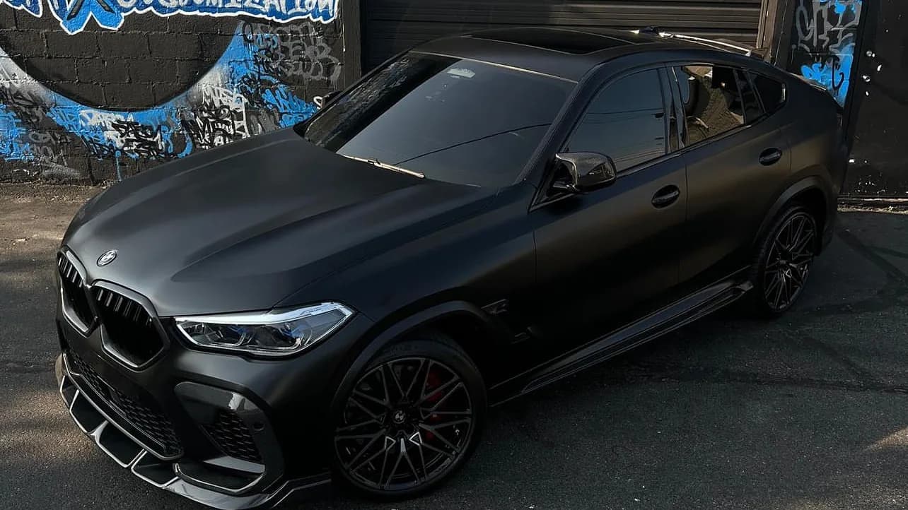 BMW X6 M in a full satin black vinyl wrap outside Buff X Customization in Dearborn Heights