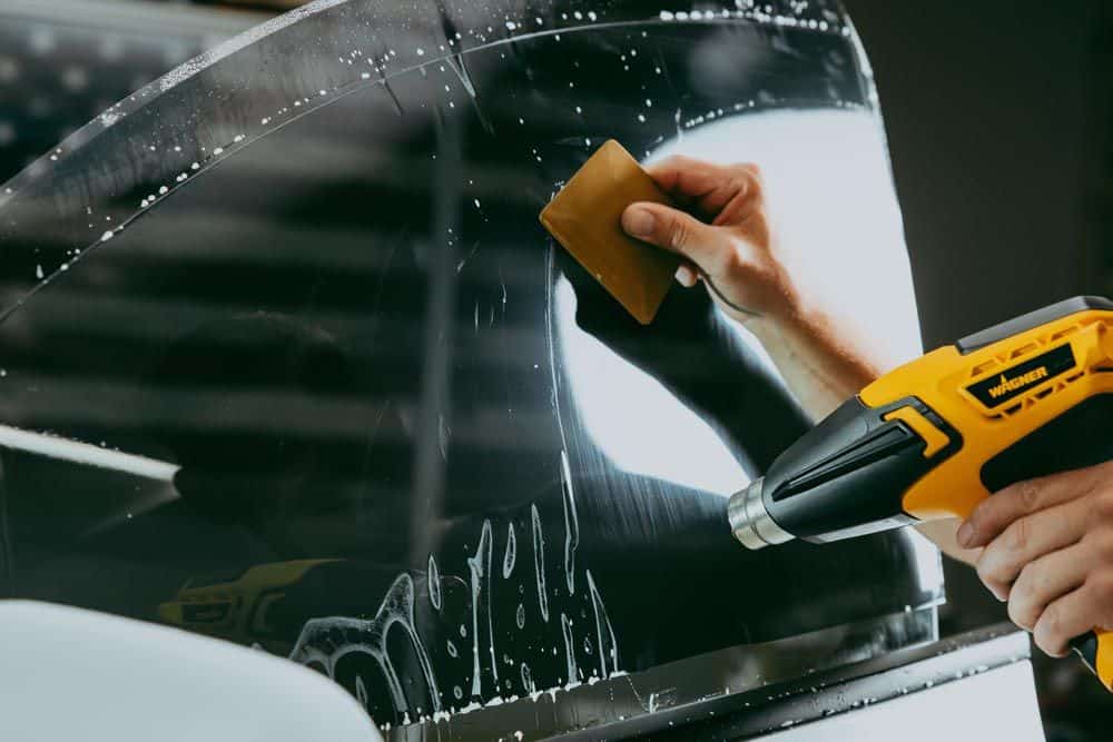 Installer squeegeeing window film onto a car window